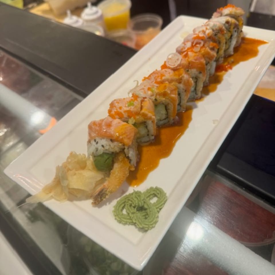 Sushi Yama's salmon and shrimp tempura sushi roll, drizzled with sauce, served with ginger and wasabi.