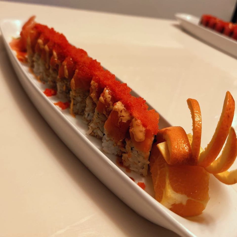 Sushi Yama's sushi roll with red roe and orange peel garnish on a white platter.