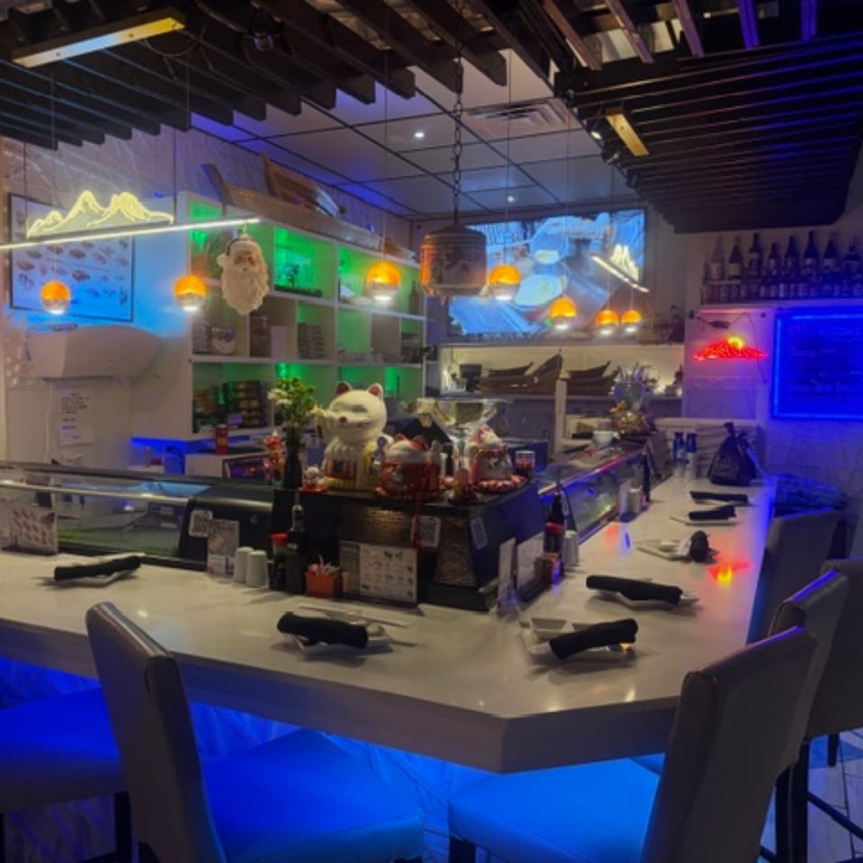 Sushi Yama's sushi bar with neon lights, bar stools, and Japanese decor.