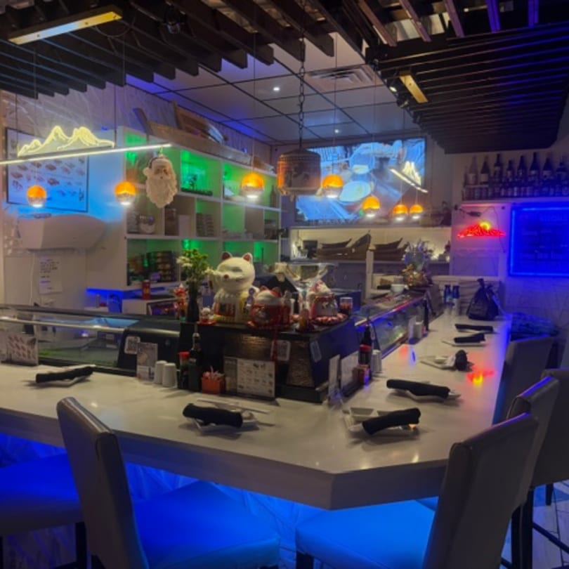 Sushi Yama's sushi bar with neon lights, bar stools, and Japanese decor.