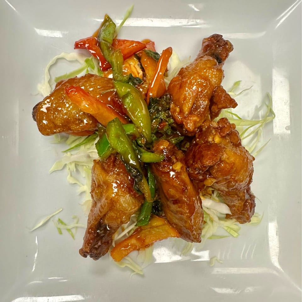 Sweet and sour chicken wings with bell peppers and cabbage on a white plate at Sushi Yama.