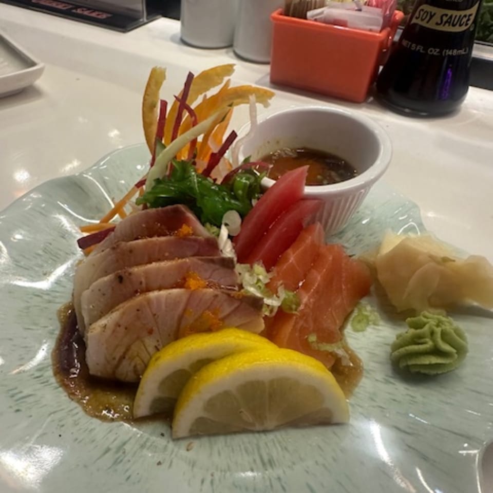 Platter of Japanese sashimi with tuna, salmon, lemon, wasabi, and pickled ginger.