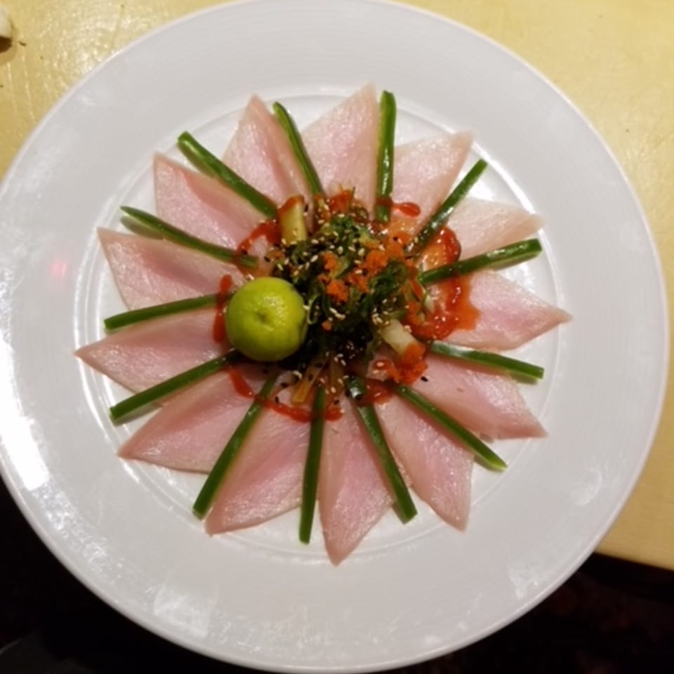 Sushi Yama's tuna sashimi arranged like a flower with green onions, sauce, and a lime.