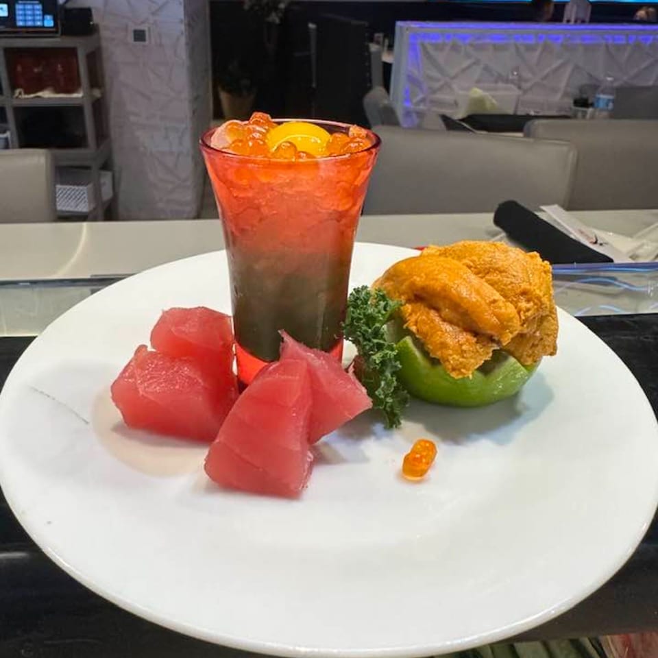 Japanese dish with tuna sashimi, uni in a lime, and a drink with roe and egg yolk.
